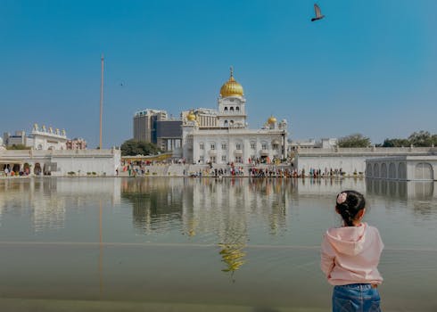 A serene view of Gurudwara Bangla Sahib with a child observing its reflection on the pond in New Delhi.