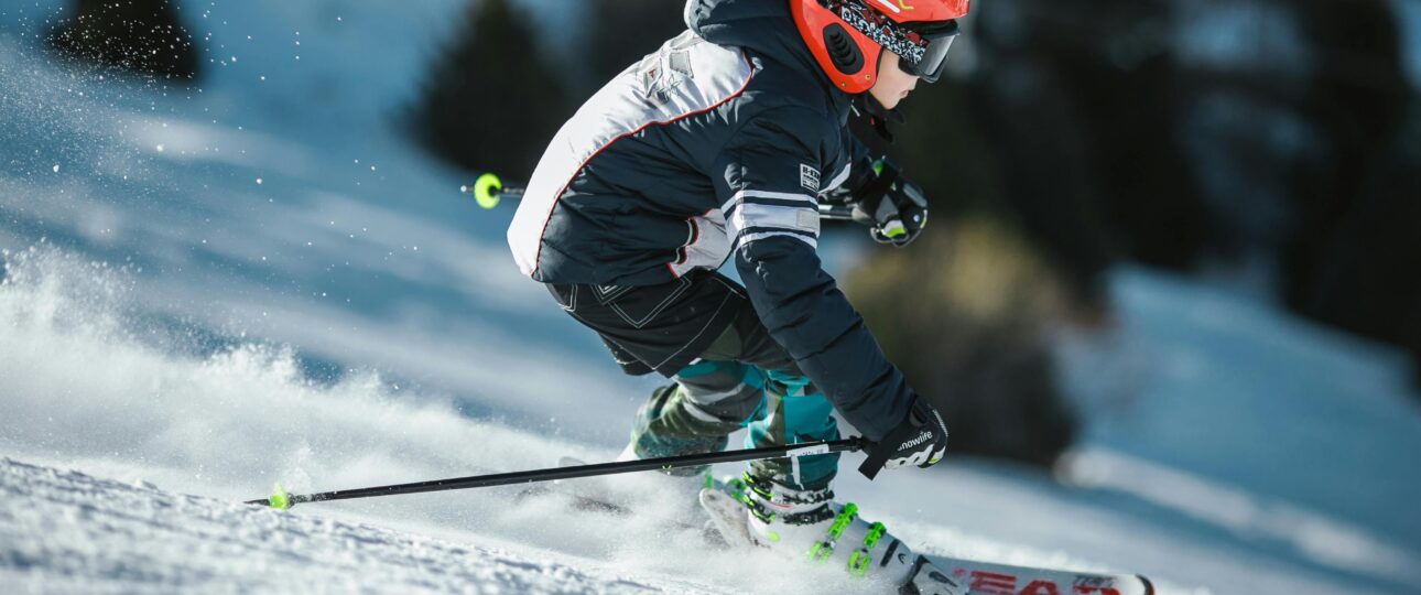 A skier in motion wearing winter gear, gliding swiftly down a snowy slope.
